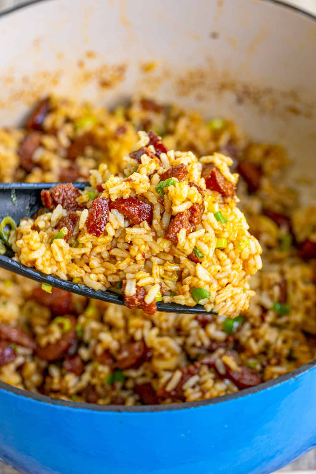 Rice on spoon being held up out of the pan.