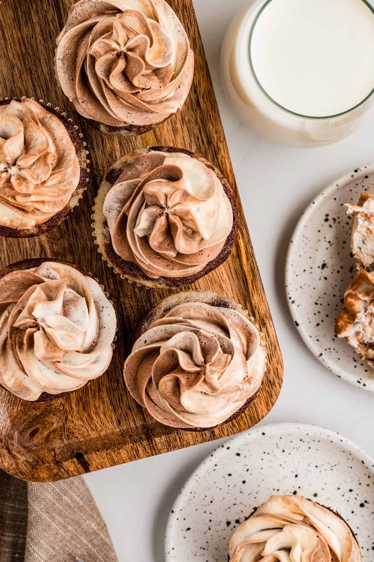 Overhead of cupcakes lined up on a wooden board.