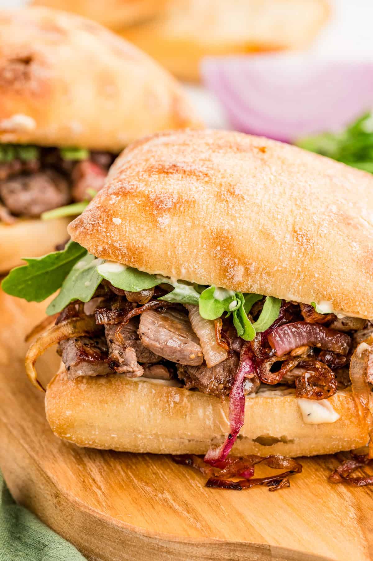 Steak Sandwich finished on wooden board showing the layers from the side.