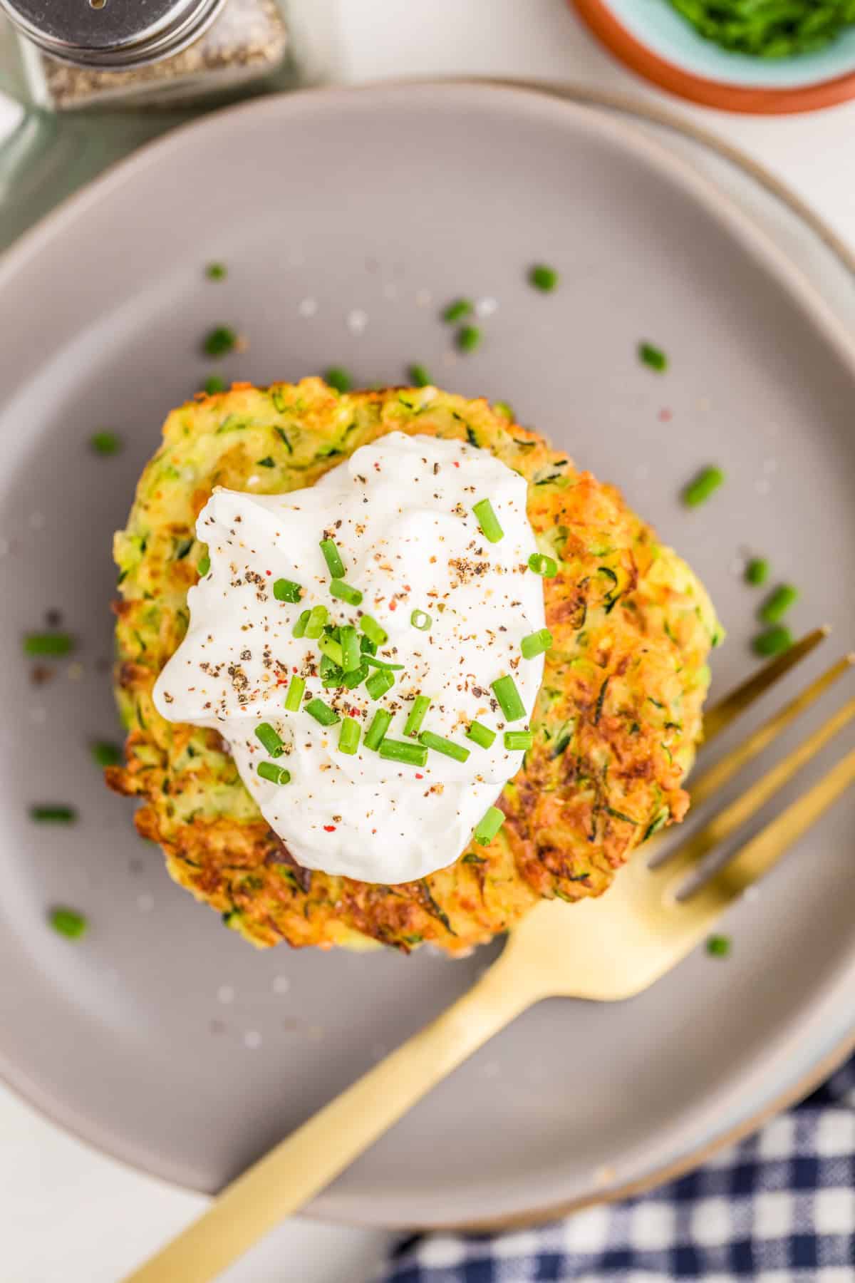 Overhead photo of fritters on grey plate showing the sour cream and chive topping.