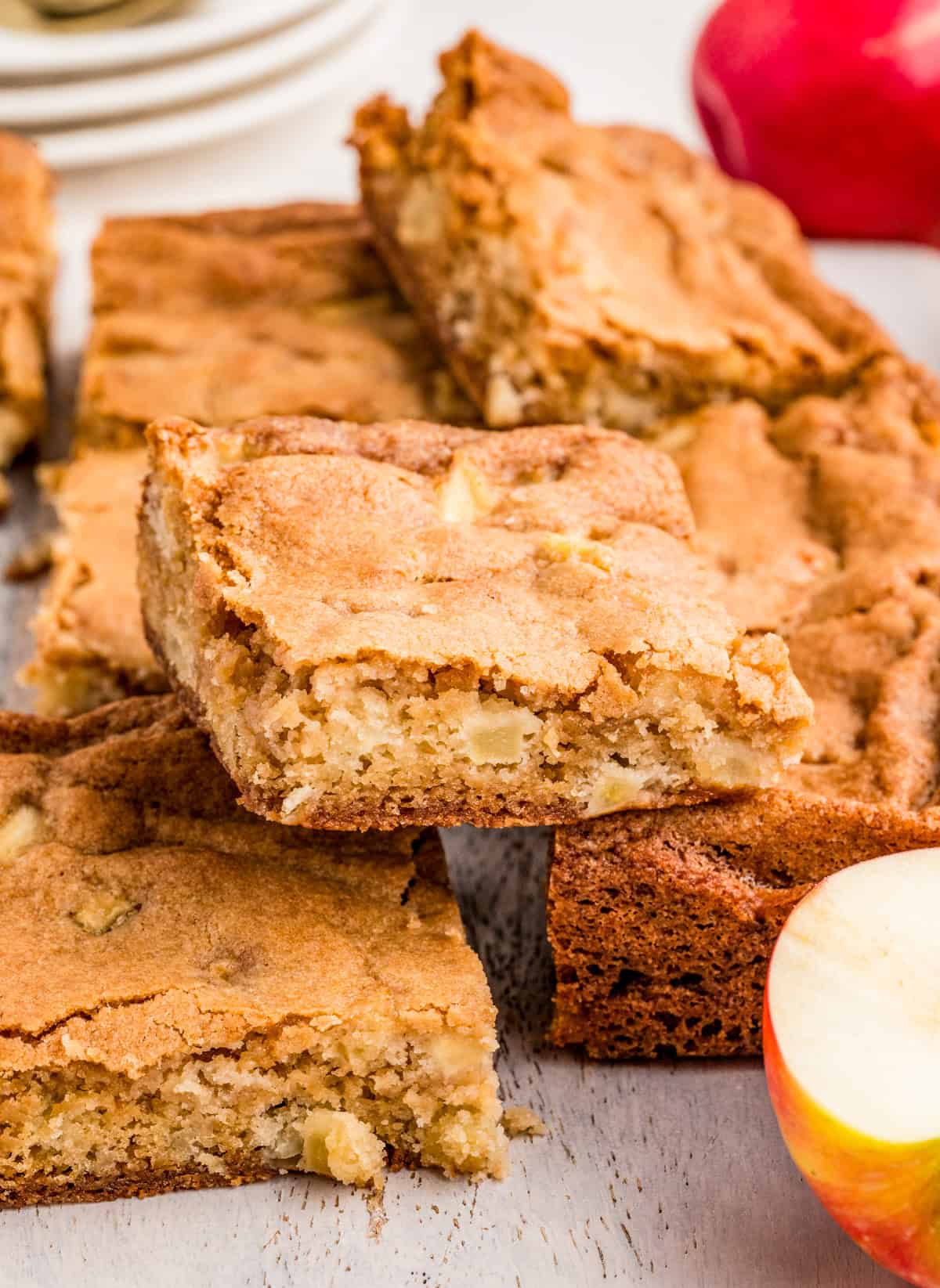 Finished Apple Blondies cut and stacked on top of one another with apples in front and back of stack.