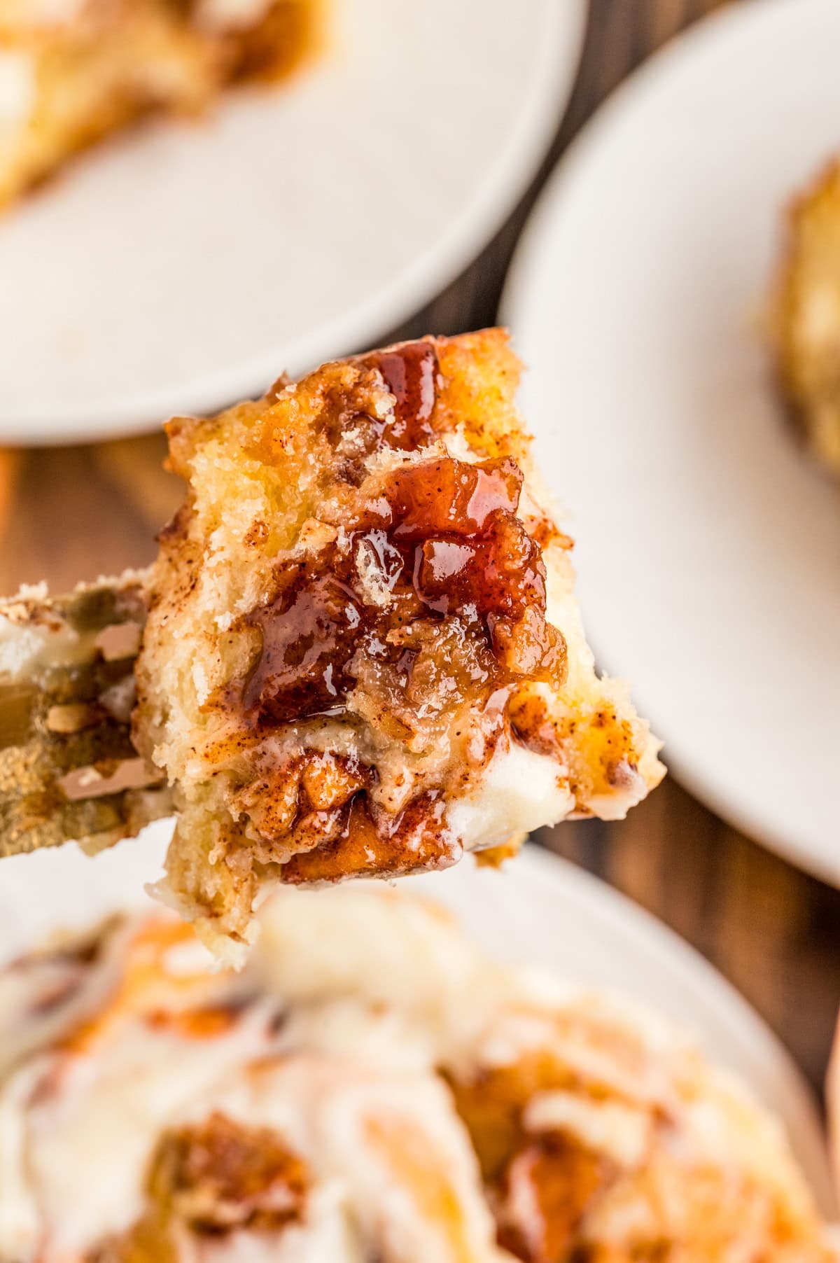 Fork holding up a bite of one of the cinnamon rolls showing the apples and cinnamon filling.