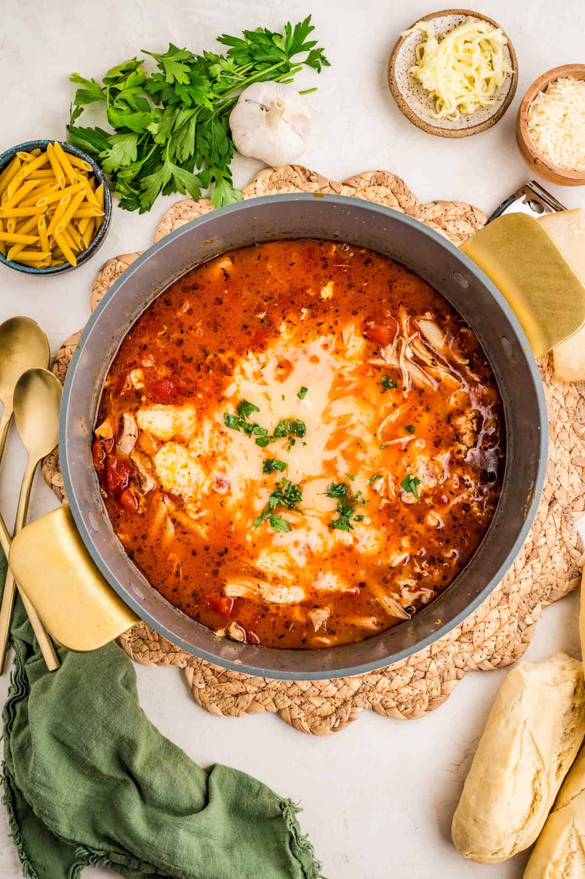 Overhead finished phot of soup in pot with bread and herbs around pot.