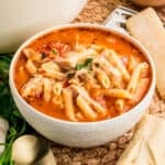 Square image of soup in white bowl showing the ingredients and toppings.