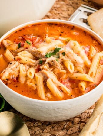 Square image of soup in white bowl showing the ingredients and toppings.