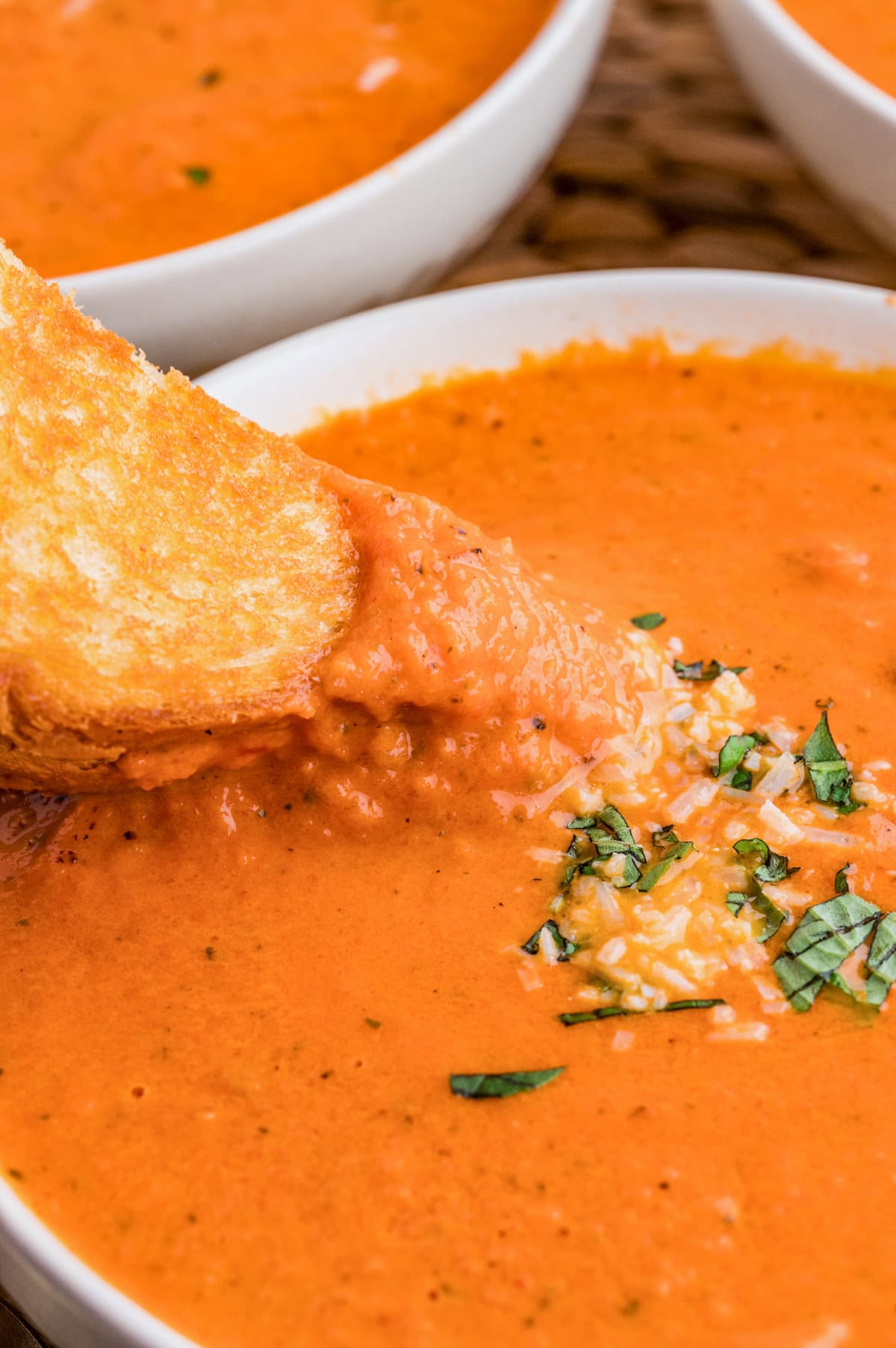 Grilled cheese sandwich being dipped in the soup.
