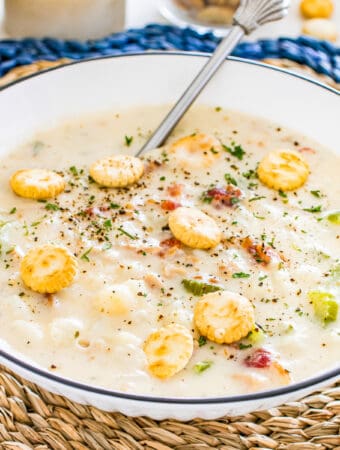 Close up of bowl with chowder in it topped with oyster crackers.