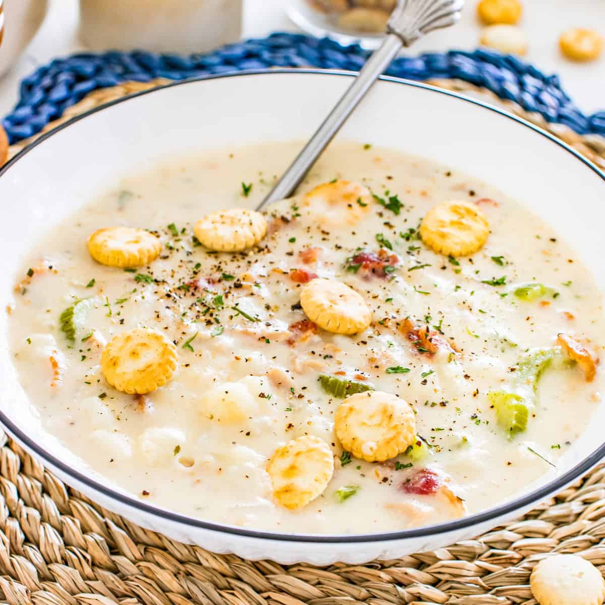 Close up of bowl with chowder in it topped with oyster crackers.