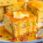 Close of of cornbread on plate with butter and syrup.