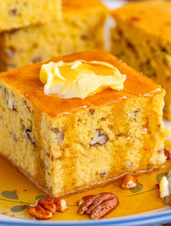 Close of of cornbread on plate with butter and syrup.