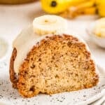 Close up of finished cake frosted and topped with a banana slice on a white plate.