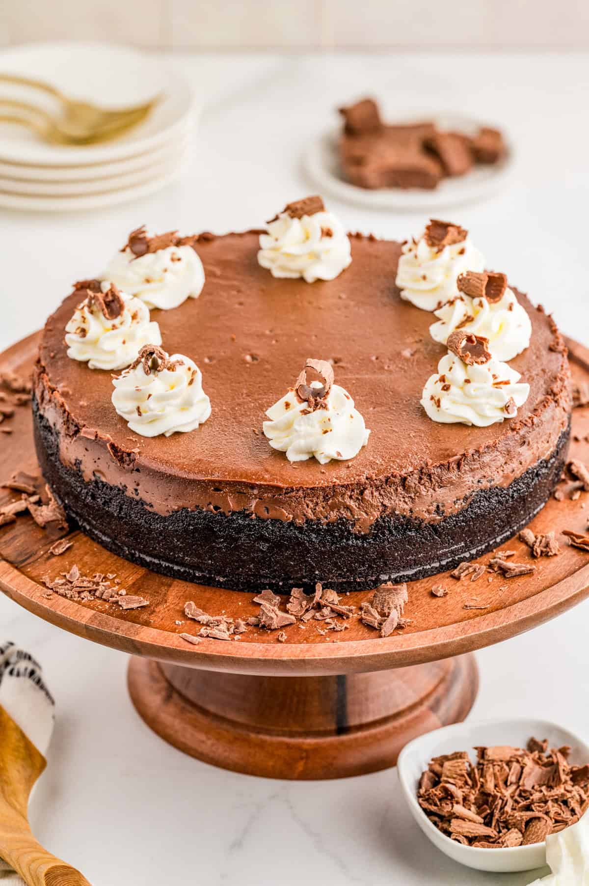 Finished and decorated Chocolate Cheesecake on wooden serving stand.
