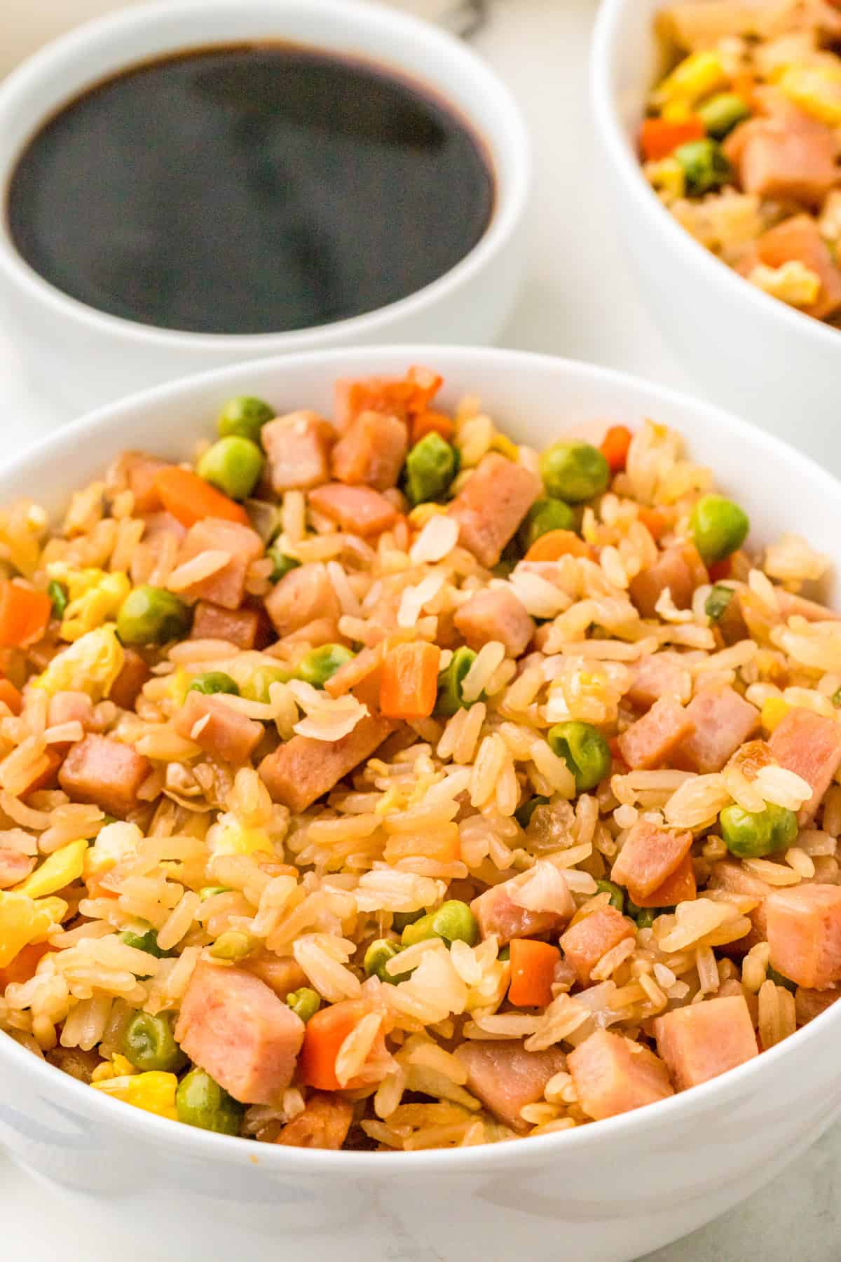 Finished Easy Spam Fried Rice in white bowl with a bowl of soy sauce in background.