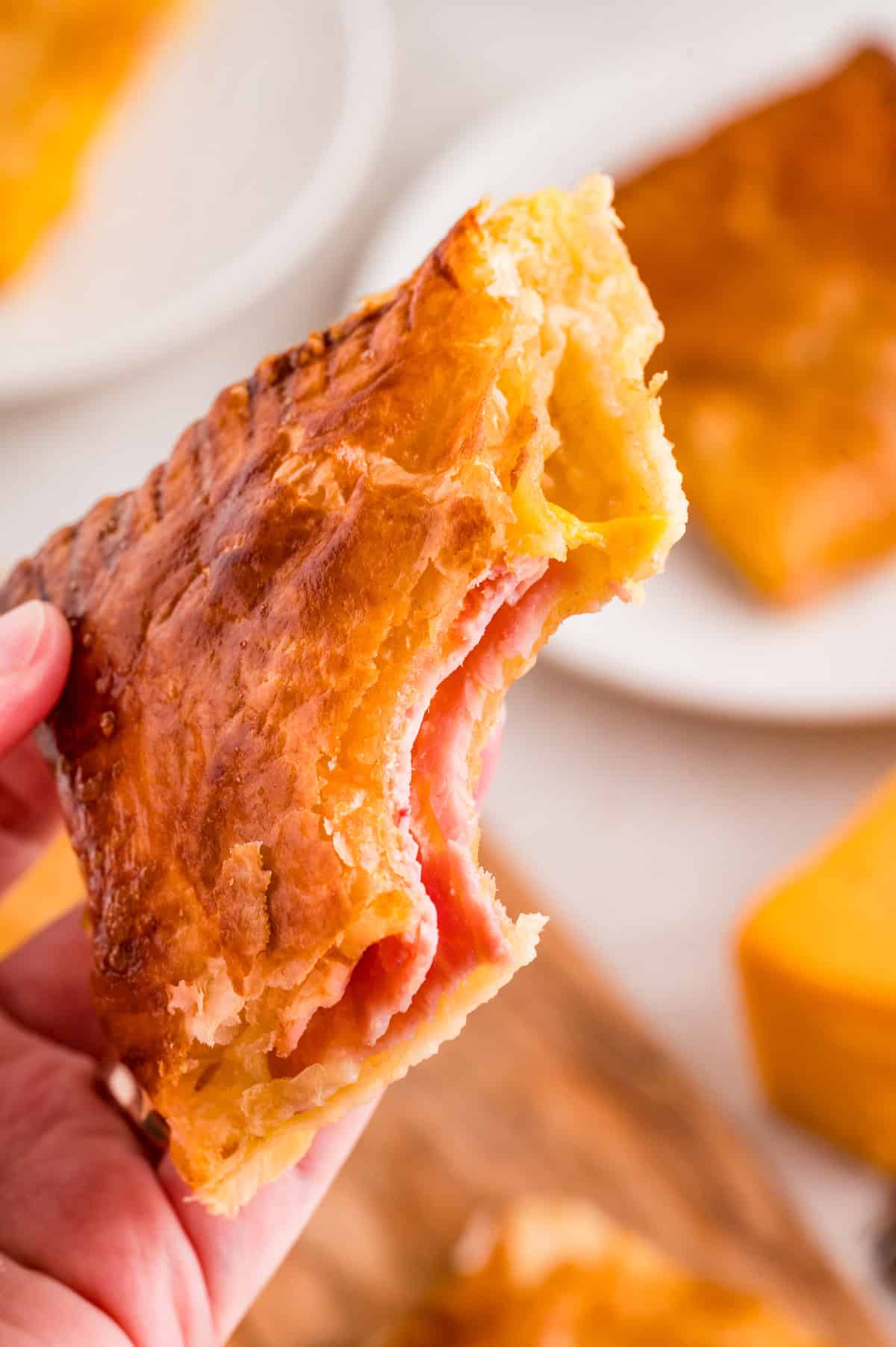 Hand holding up one of the pastries with a bite taken out of it.