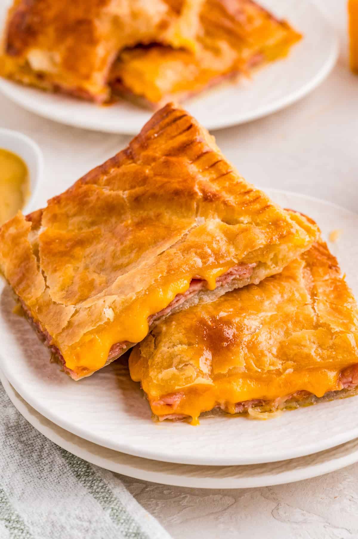 Two stacked Ham and Cheese Puff Pastry on white plate.