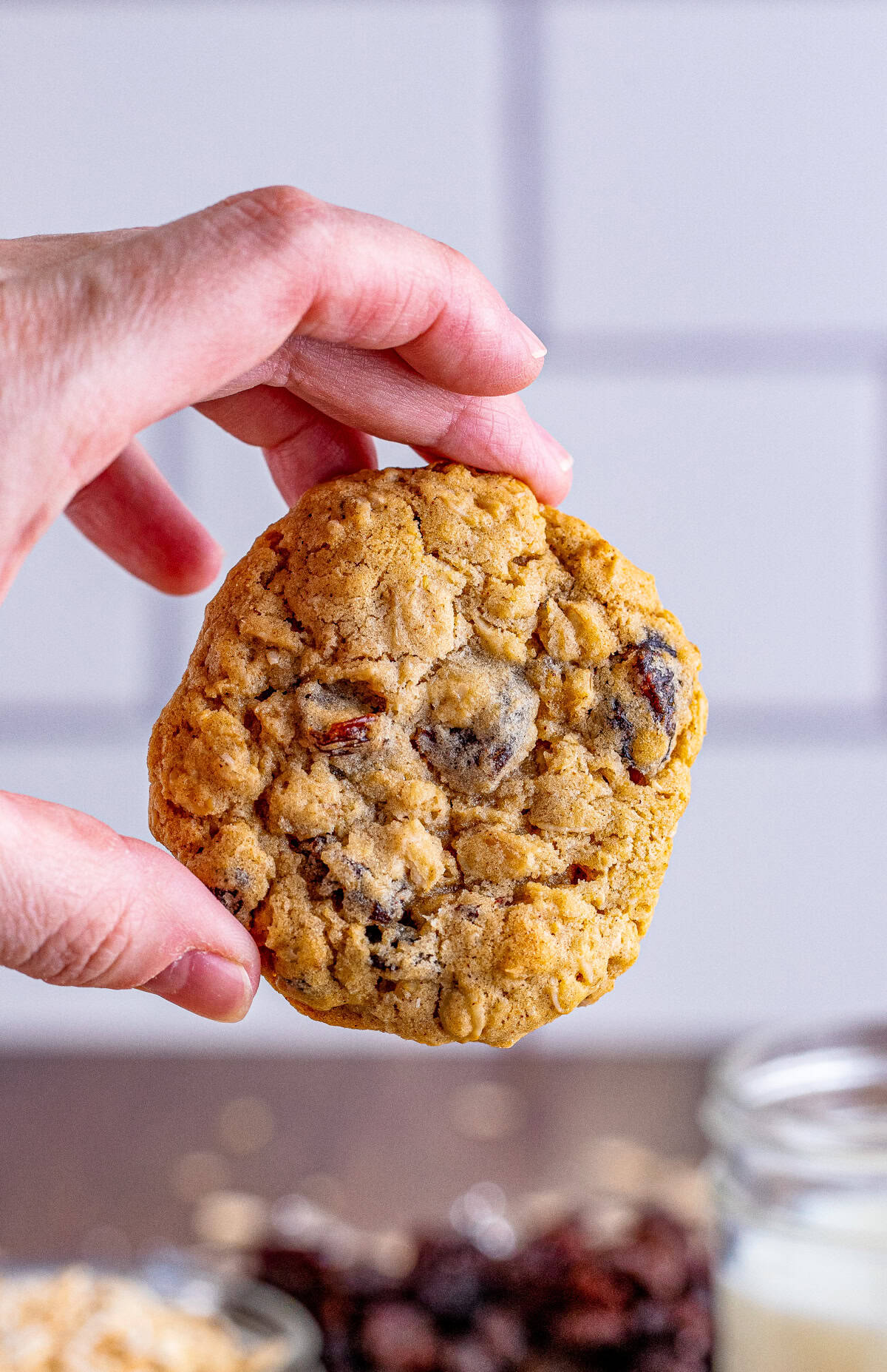 Hand holding up one of the finished Oatmeal Raisin Cookies.