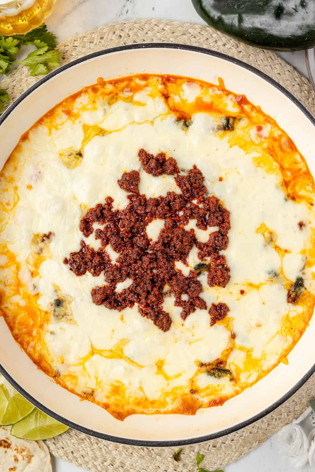 Finished Queso Fundido Recipe in baking dish, topped with chorizo.