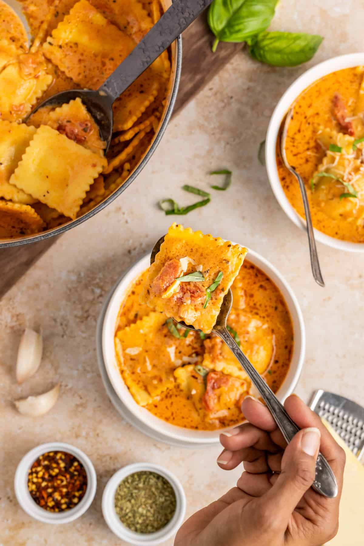 Overhead of soup in bowl with a spoon holding up one of the raviolis.