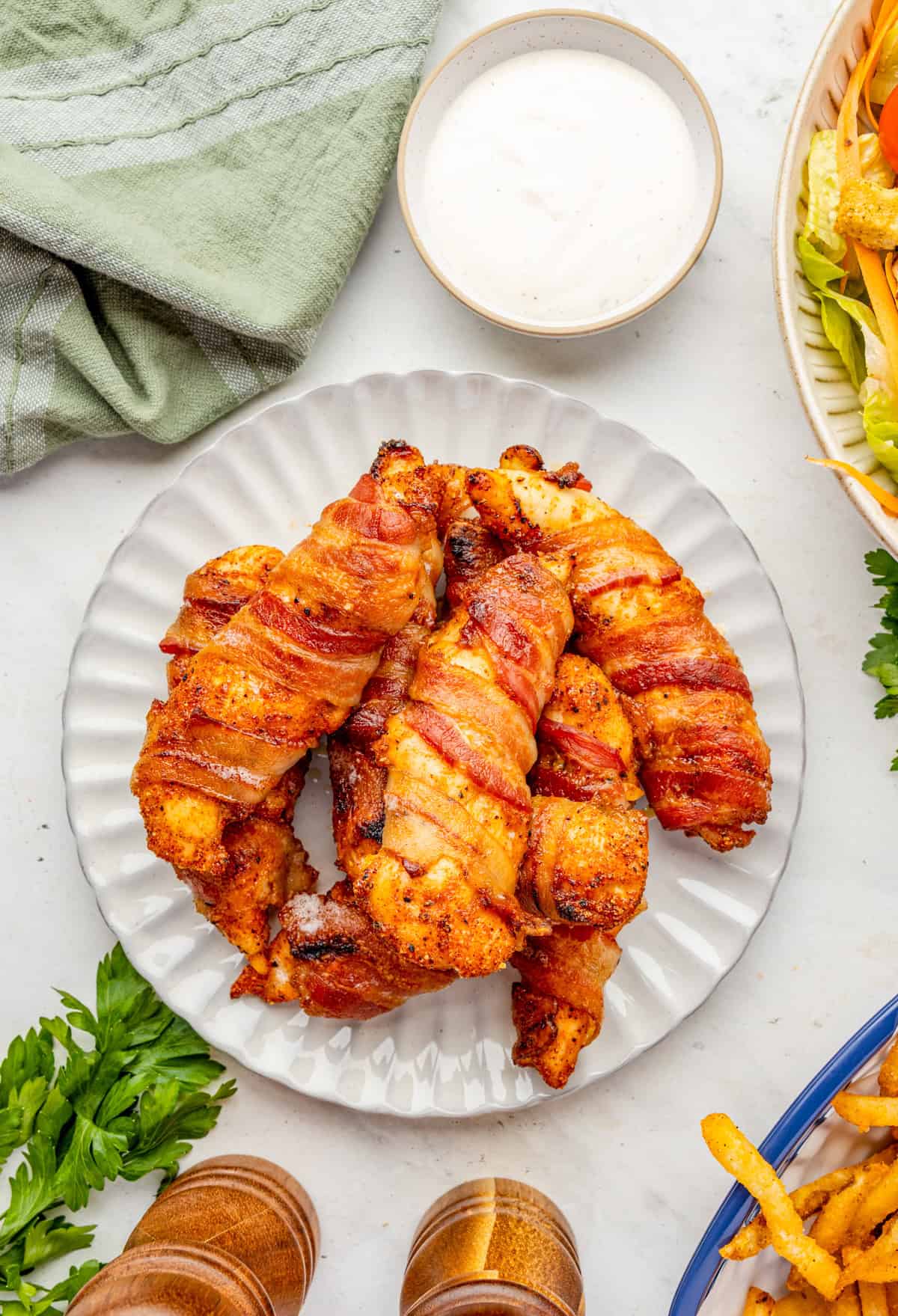 Overhead of chicken tenders on white plate with dipping sauce next to plate.