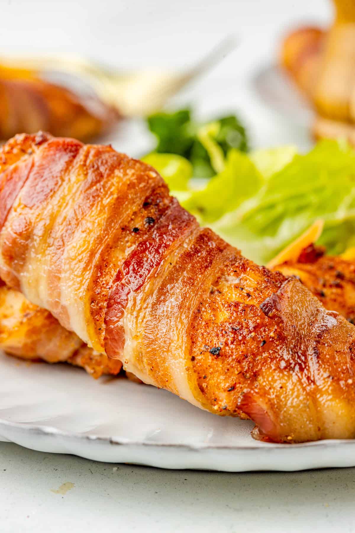 Close up of one of the Bacon Wrapped Chicken Tenders showing the crispy bacon.